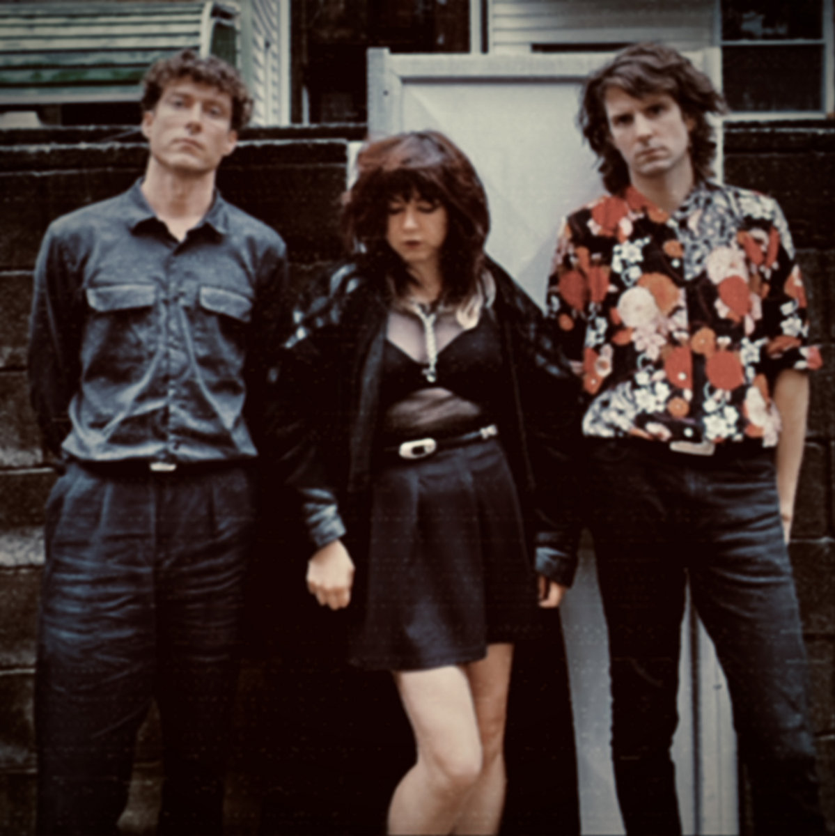 the members of spiral path standing against a stone wall.